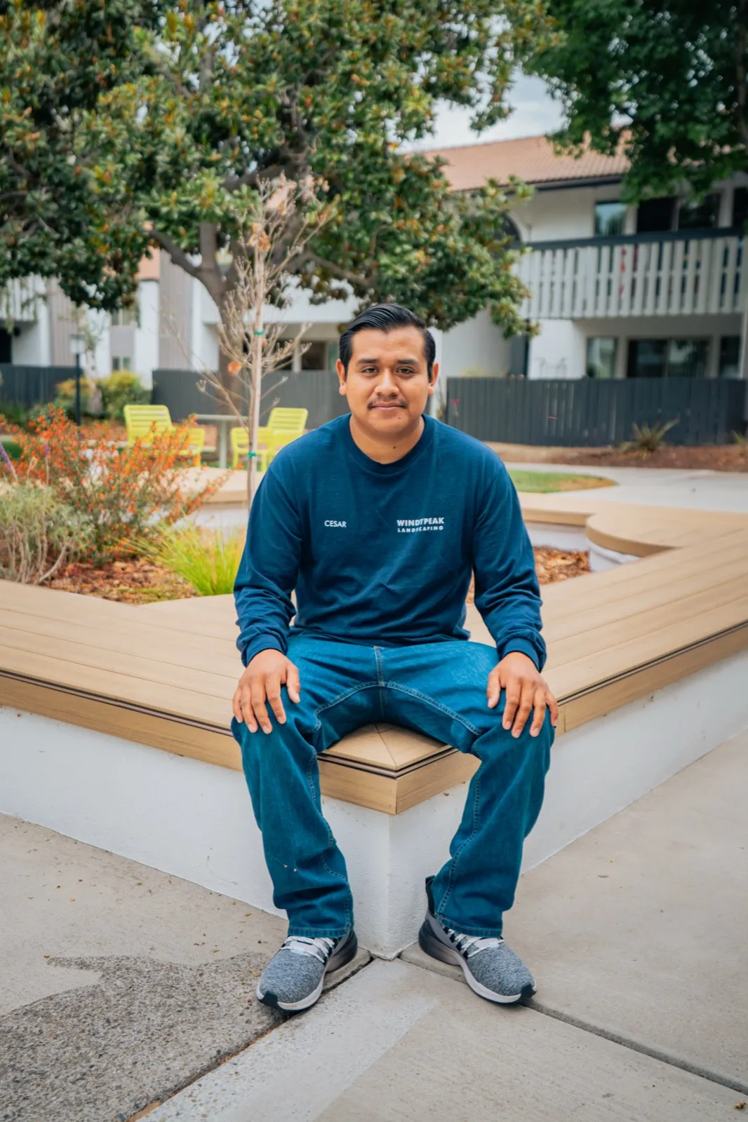Cesar of WindyPeak Landscaping, seated on a planter bench his crew built